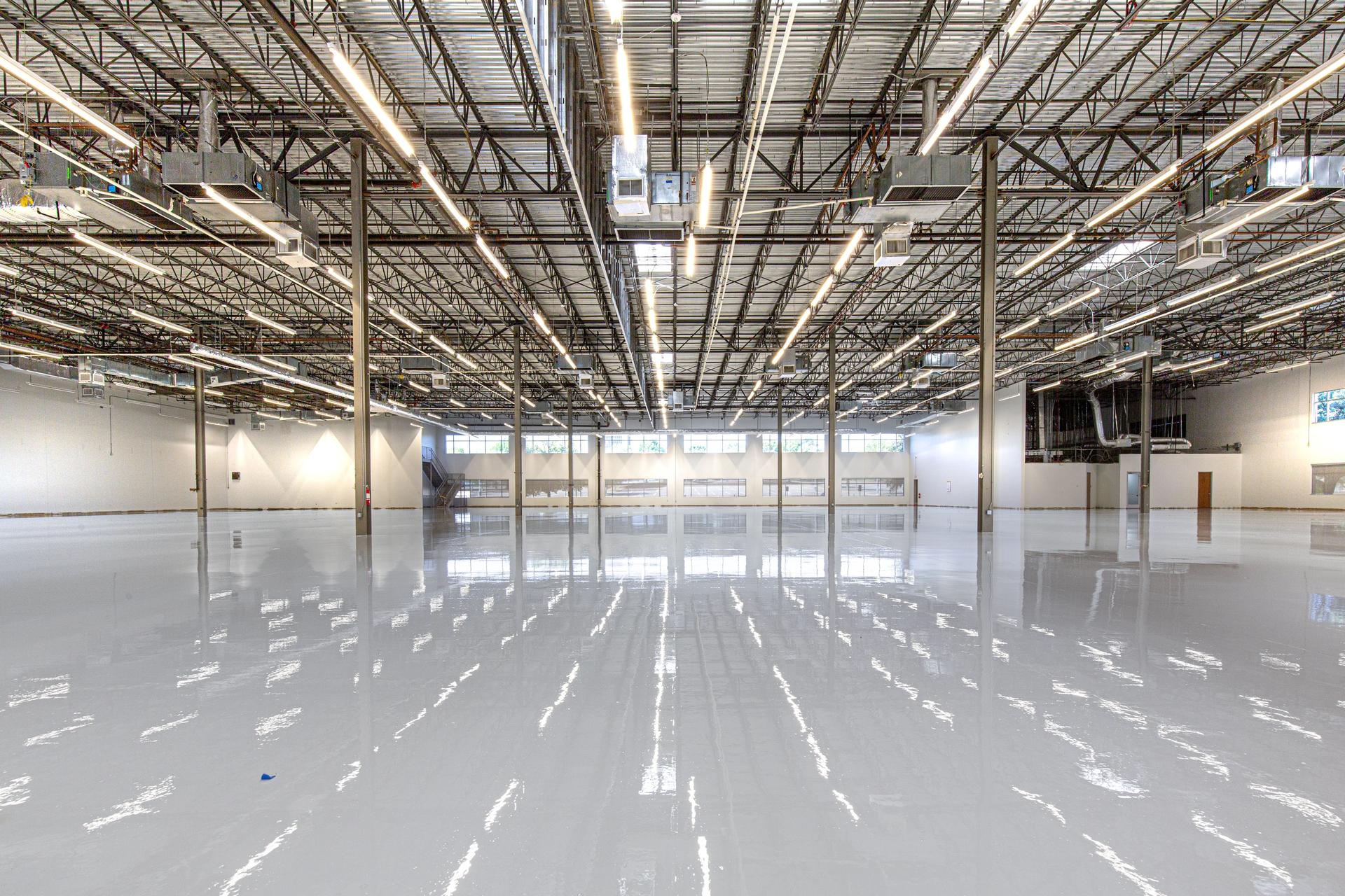 Empty warehouse with glossy gray epoxy flooring under skylights